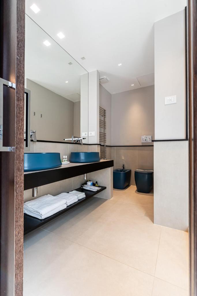 La salle de bains est pourvue de 2 lavabos bleus et de 2 toilettes. dans l'établissement Ngonia Bay Boutique Hotel, à Milazzo