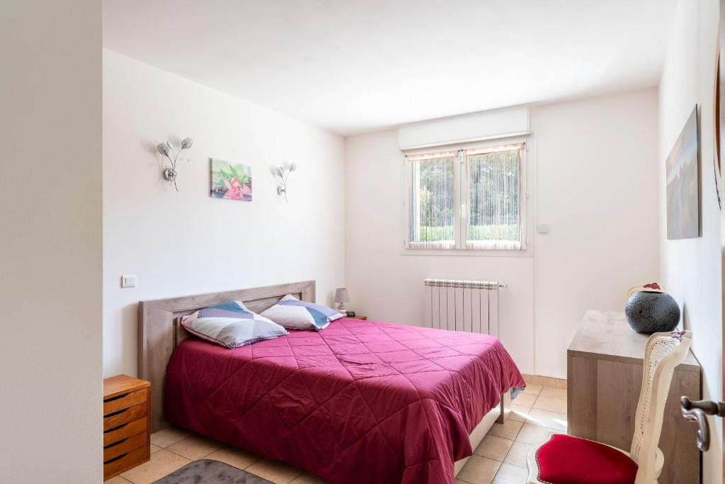 une chambre avec un lit avec un couvre-lit rouge dans l'établissement Gîte les oliviers, à Saint-Laurent-la-Vernède