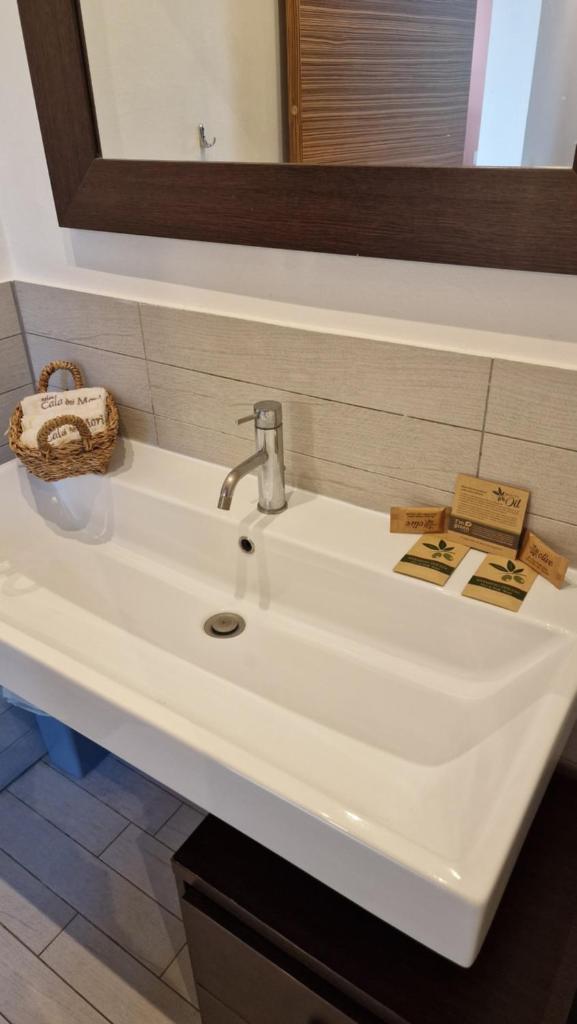 un lavabo blanc dans une salle de bain avec un miroir dans l'établissement Cala Dei Mori, à Livourne 72 autres photos