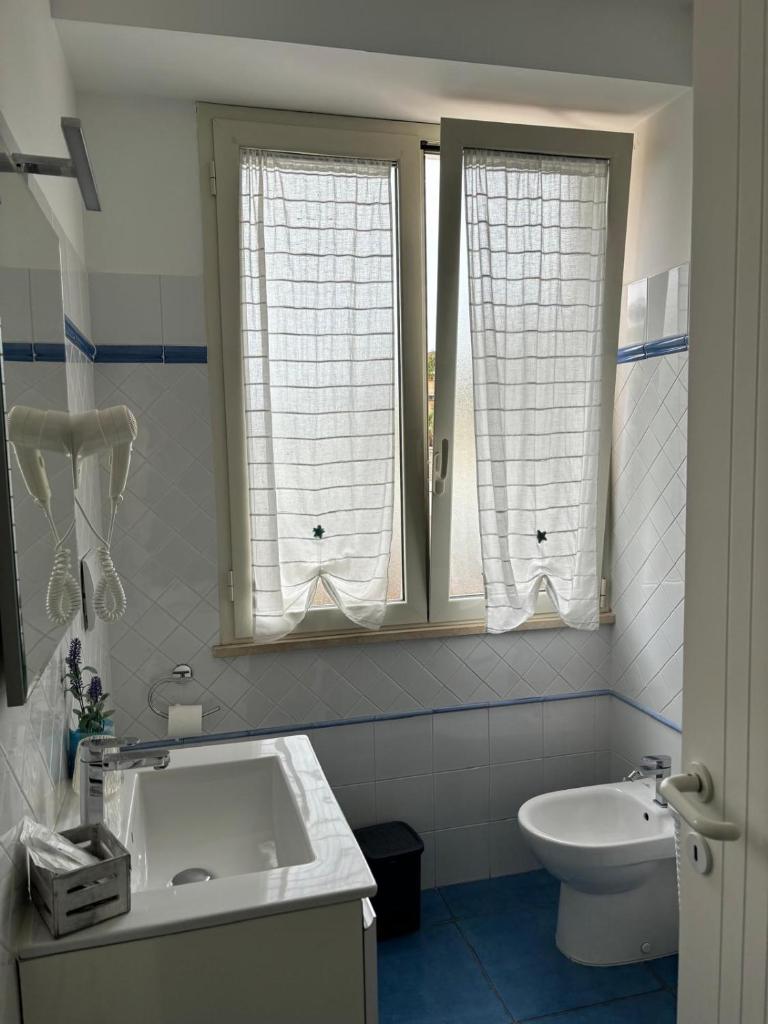 La salle de bains est pourvue d'un lavabo, de toilettes et de 2 fenêtres. dans l'établissement Acca residence, à Terracine
