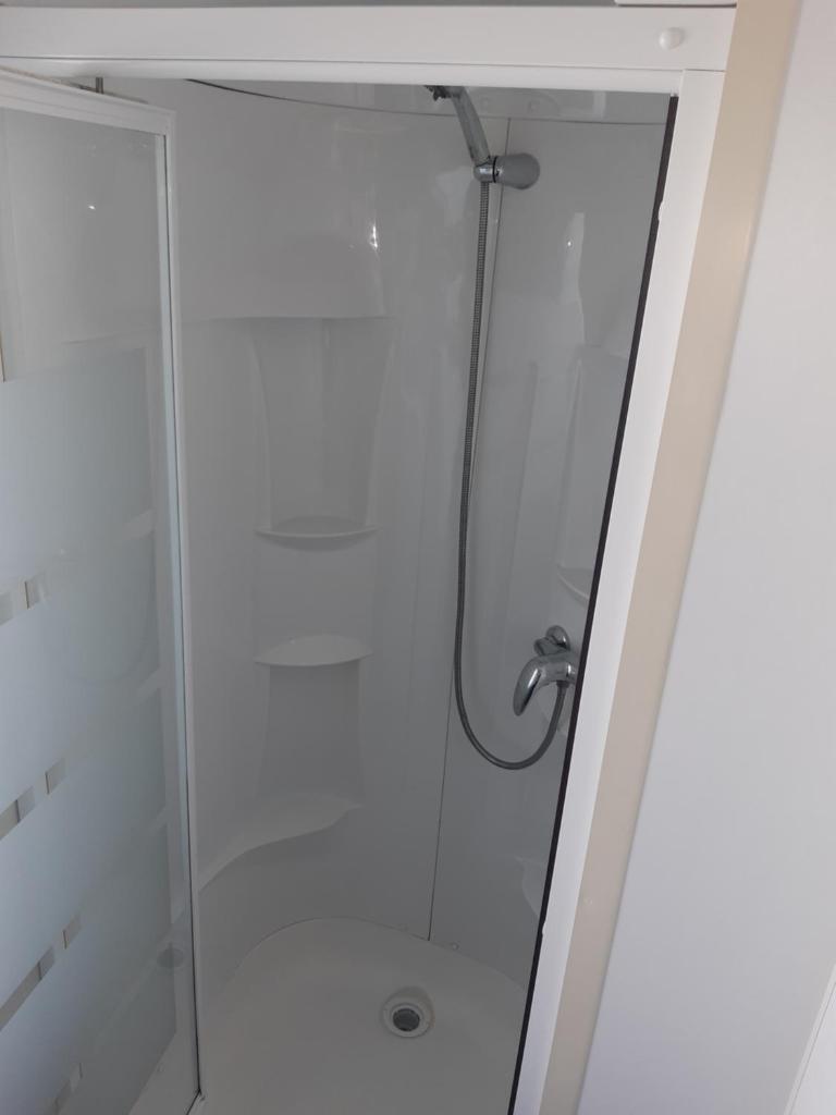 une douche dans une salle de bain avec une porte vitrée dans l'établissement Mobile home S004, à Lancieux