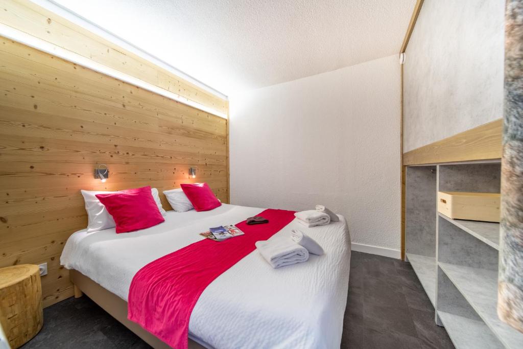 une chambre avec un grand lit avec des oreillers rouges dans l'établissement Résidence Kocoon Les Karellis - Pass activités inclus, à Montricher-Albanne