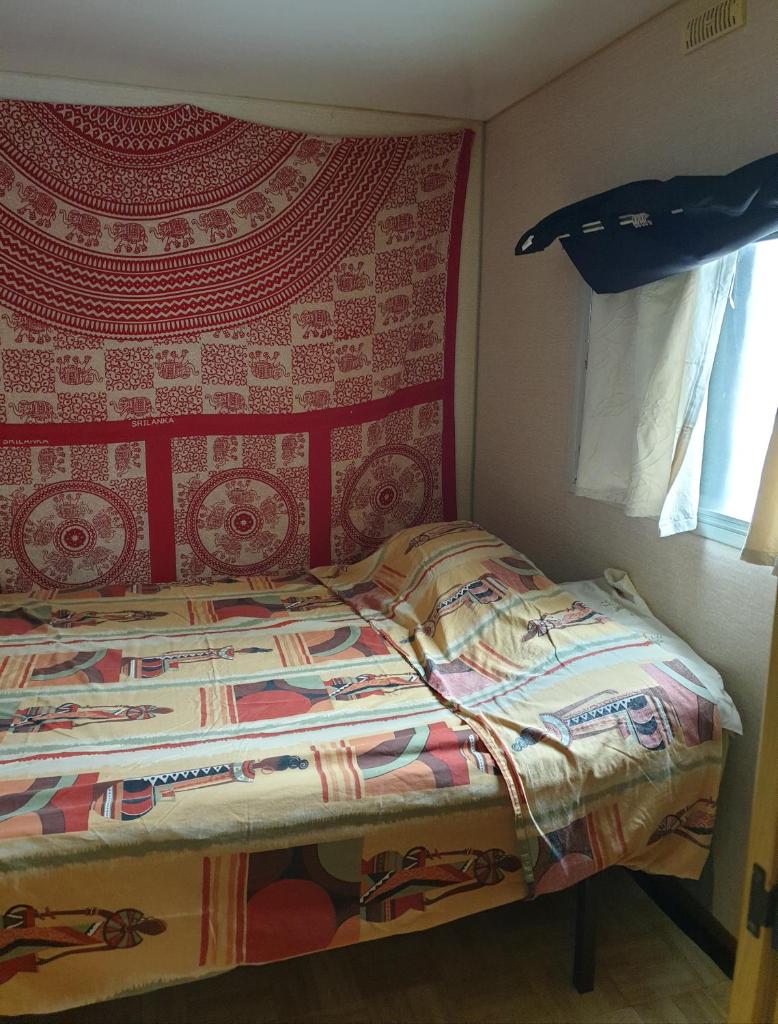 Ce lit se trouve dans une chambre dotée d'un mur rouge. dans l'établissement Mobil home chez un particulier pour 1 à 4 personnes à 800 m de la plage de Valras pas dans un camping, à Sérignan 9 autres photos