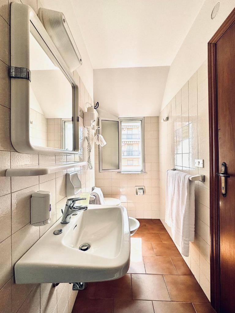 une salle de bain blanche avec un lavabo et un miroir dans l'établissement Hotel Blumen, à San Benedetto del Tronto