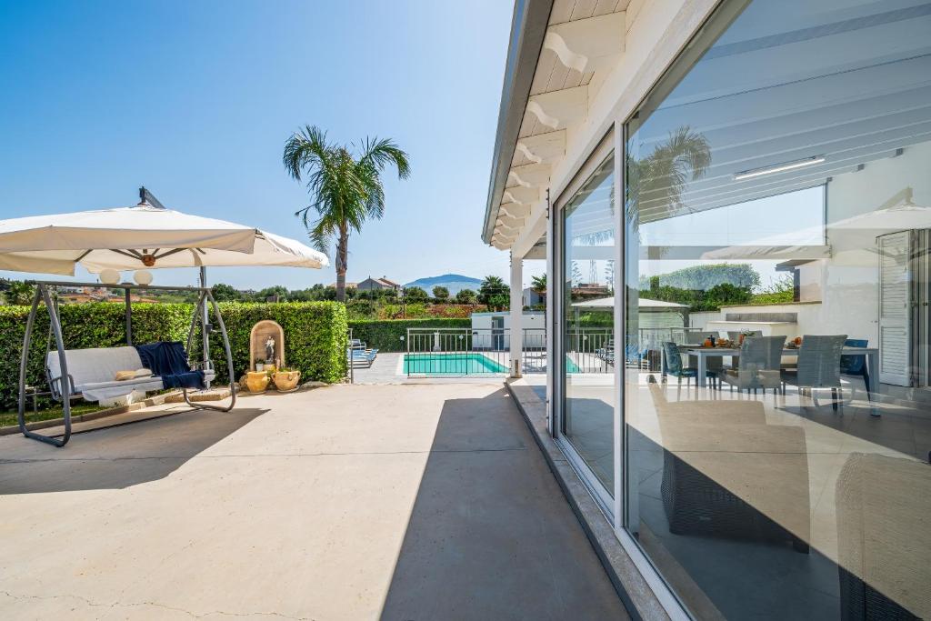 une terrasse avec une table et un parasol dans l'établissement Villa DellUlivo, à Alcamo