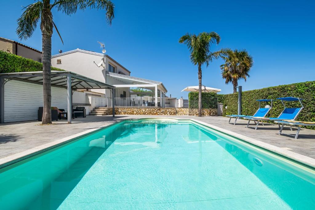 une piscine avec deux chaises bleues et une maison dans l'établissement Villa DellUlivo, à Alcamo