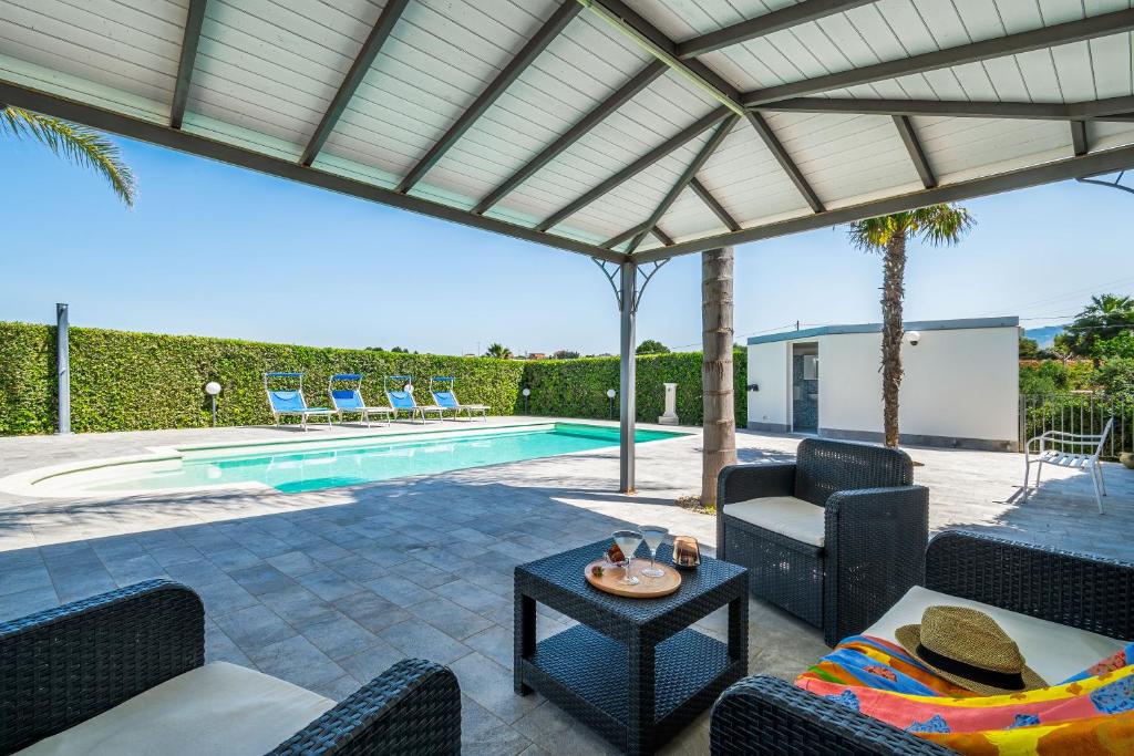 une terrasse avec des chaises, une table et une piscine dans l'établissement Villa DellUlivo, à Alcamo