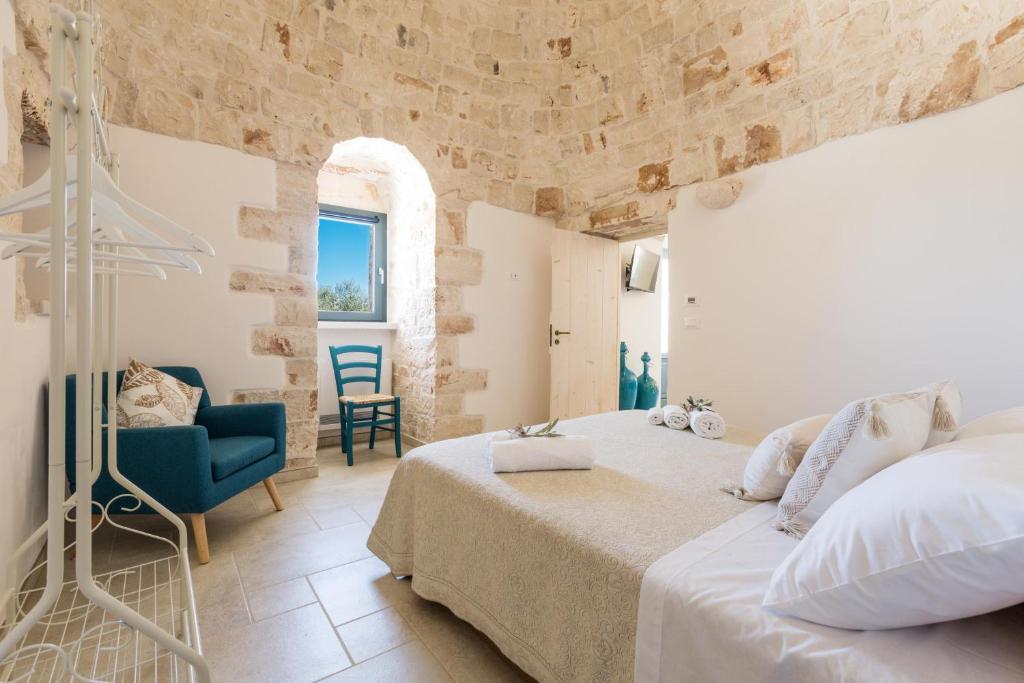 une chambre avec un lit et une chaise bleue dans l'établissement Trulli Ulivo di Puglia by BarbarHouse, à Selva di Fasano