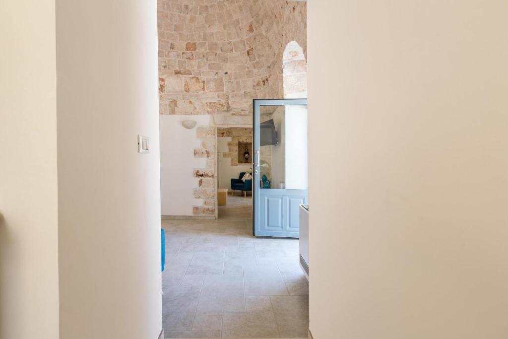 un couloir avec des murs blancs et un mur en briques dans l'établissement Trulli Ulivo di Puglia by BarbarHouse, à Selva di Fasano