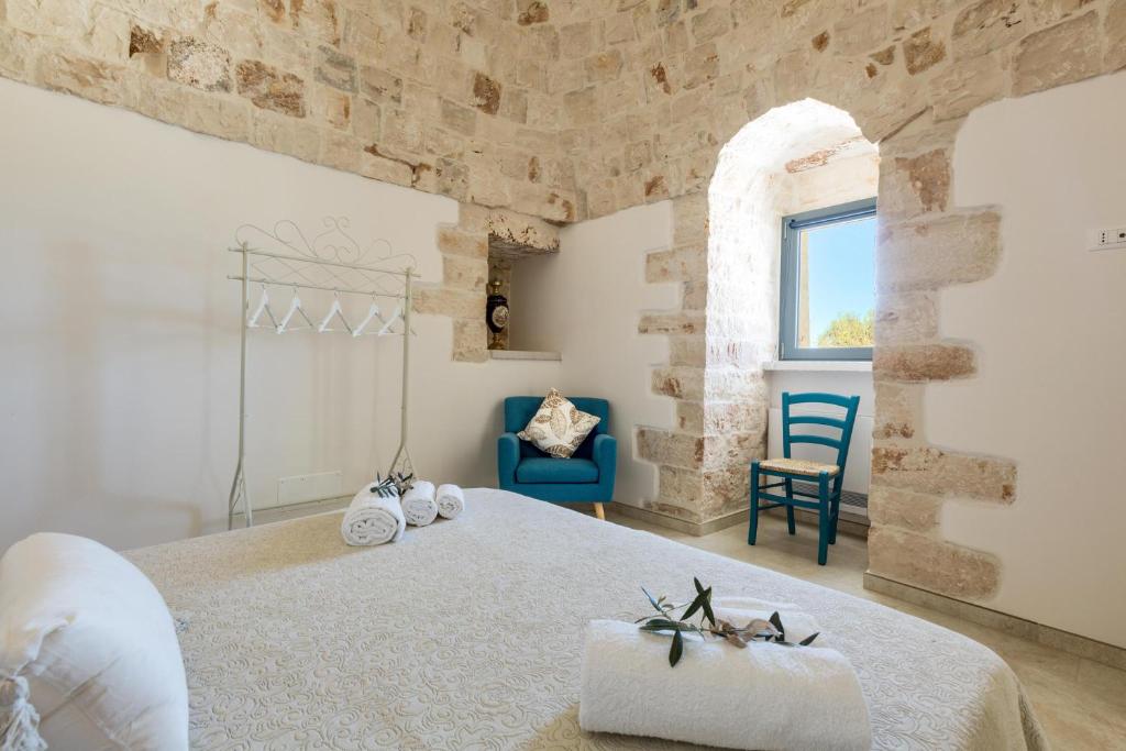 une chambre avec un lit et une chaise bleue dans l'établissement Trulli Ulivo di Puglia by BarbarHouse, à Selva di Fasano 33 autres photos