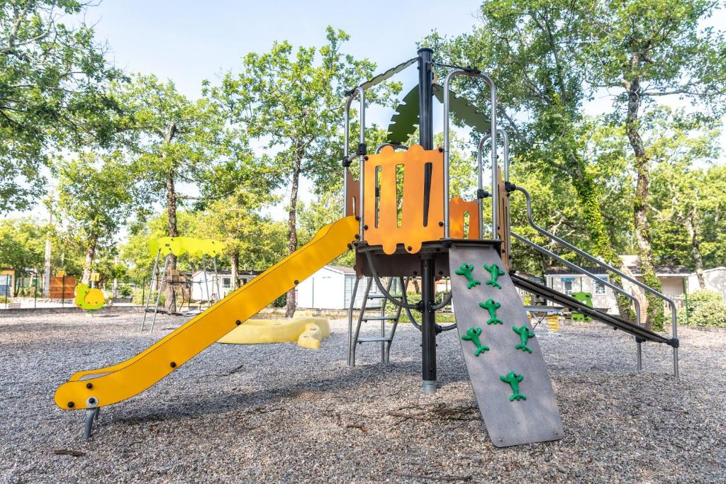 une aire de jeux avec toboggan jaune dans un parc dans l'établissement Camping Domaine de Chaussy, à Lagorce