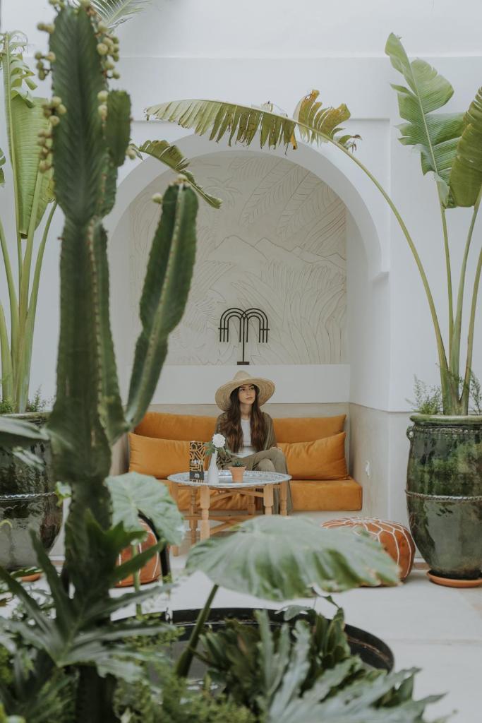 une femme assise sur un canapé dans une pièce avec des plantes dans l'établissement Riad Dar M, à Marrakech