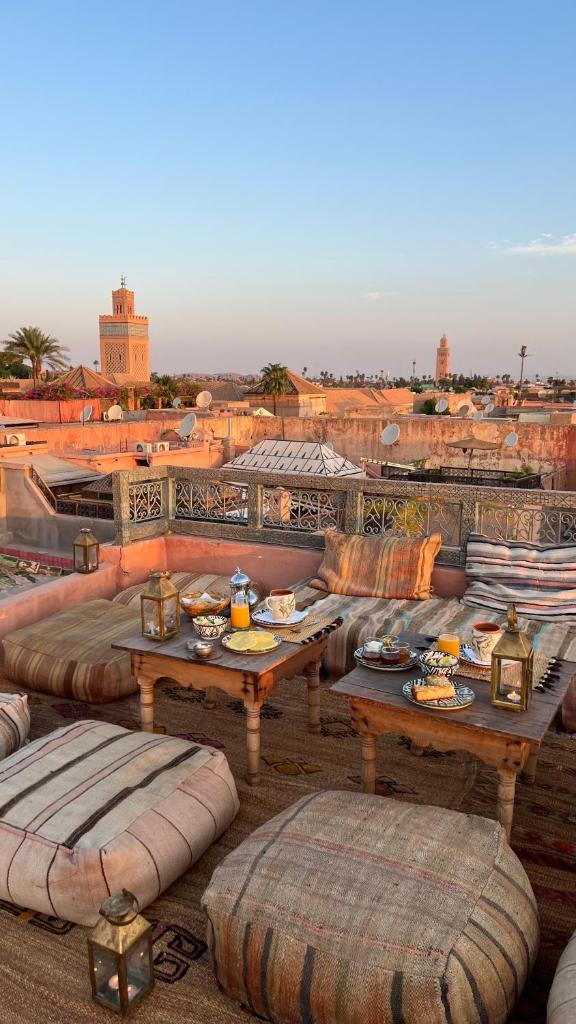 un patio avec des canapés et des tables sur le toit dans l'établissement Riad Ksar Fawz & Spa, à Marrakech
