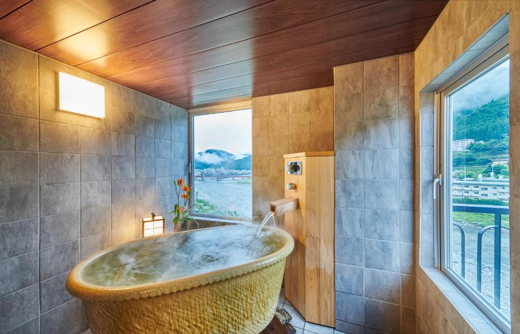 La salle de bains est pourvue d'une grande baignoire et d'une fenêtre. dans l'établissement Yamagataya, à Gero