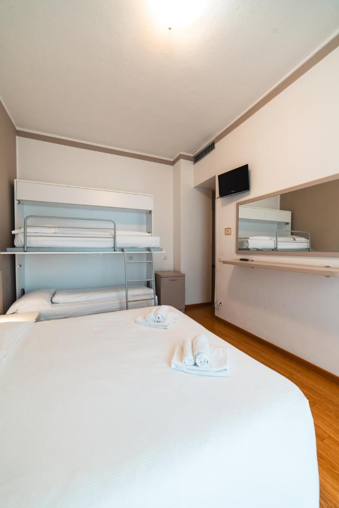 une chambre avec un grand lit blanc et une télévision dans l'établissement Hotel Del Corso, à Bibione