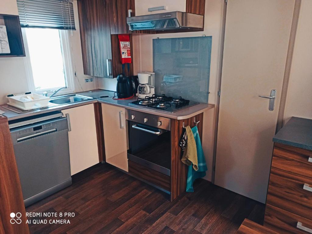 Il comprend une petite cuisine équipée d'une cuisinière et d'un évier. dans l'établissement Mobil home l'oliverie, à Valras-Plage