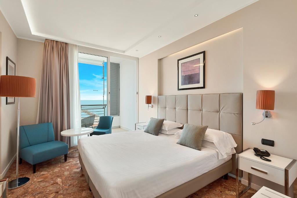 une chambre avec un grand lit et une chaise bleue dans l'établissement Hotel Excelsior, à Marina di Massa