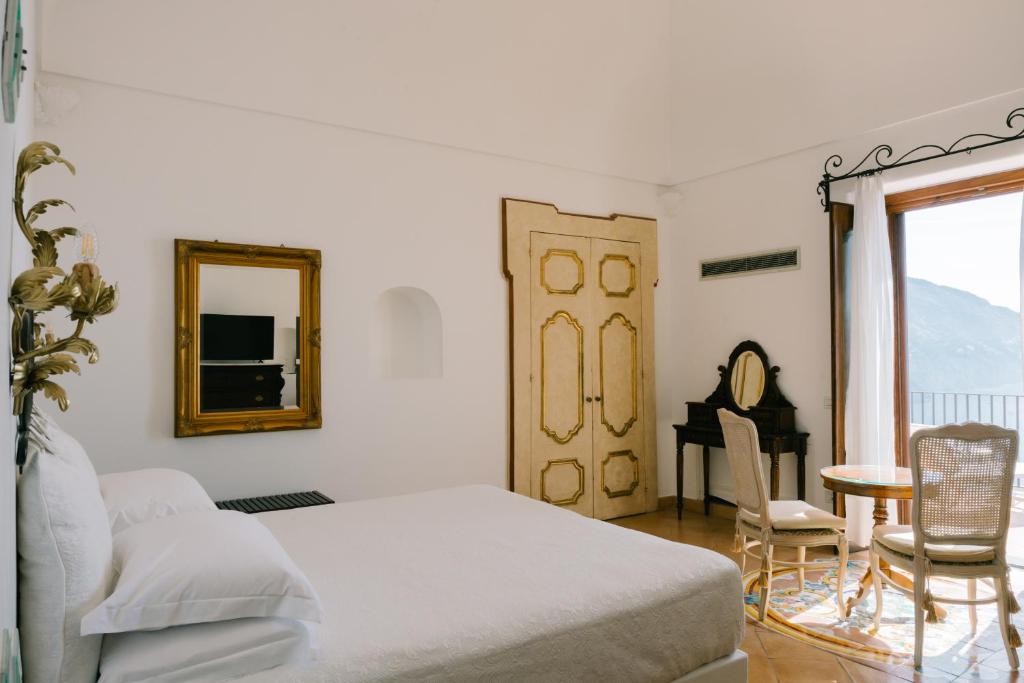 une chambre avec un lit, un miroir et une table dans l'établissement Villa Principe Giovanni, à Positano