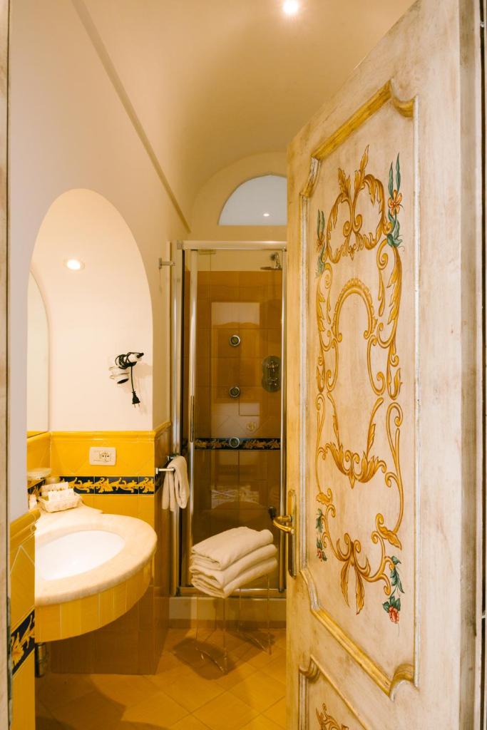 La salle de bains est pourvue d'une douche, d'un lavabo et d'une porte. dans l'établissement Villa Principe Giovanni, à Positano