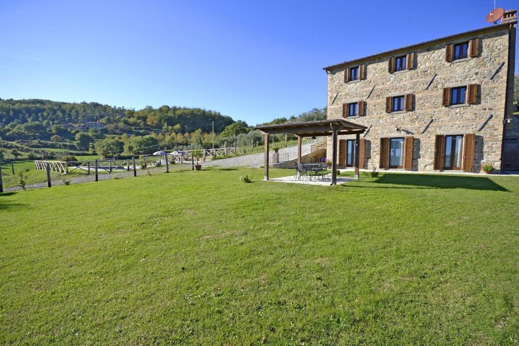 un bâtiment en pierre avec une pelouse devant lui dans l'établissement Villa Fiordaliso, à Poggioni