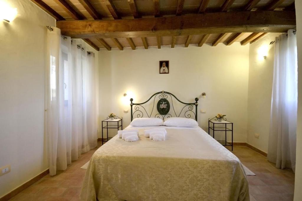 une chambre avec un grand lit avec des draps et des oreillers blancs dans l'établissement Villa Fiordaliso, à Poggioni
