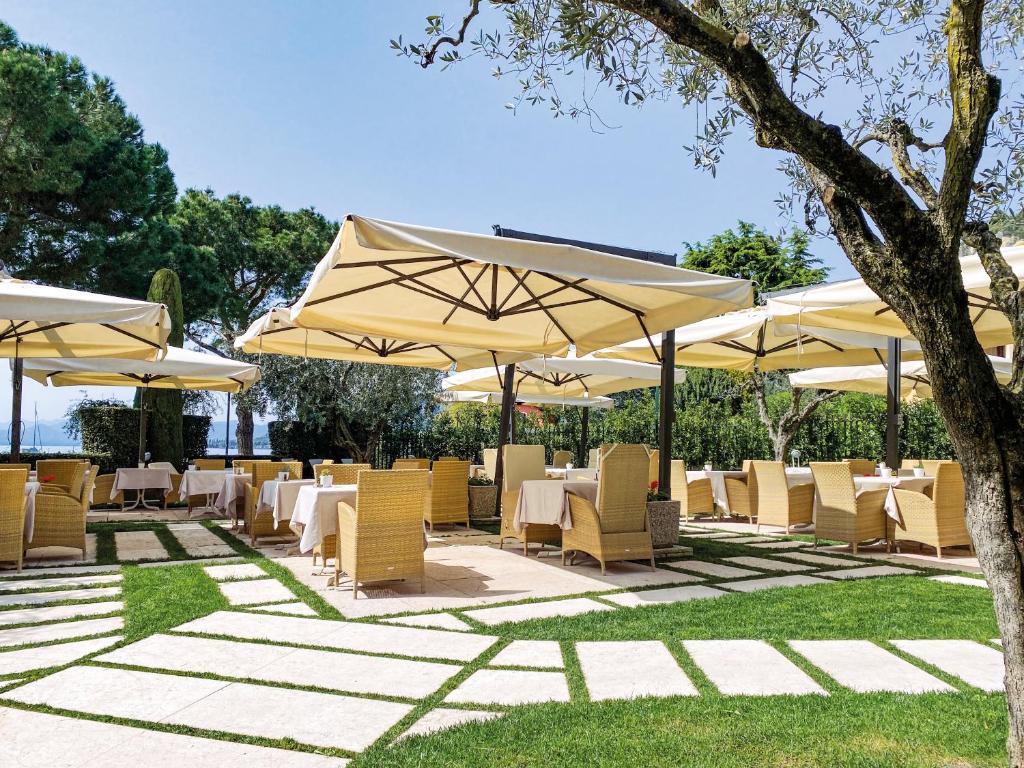 un restaurant avec des tables et des chaises sous des parasols dans l'établissement Hotel Sportsman, à Bardolino