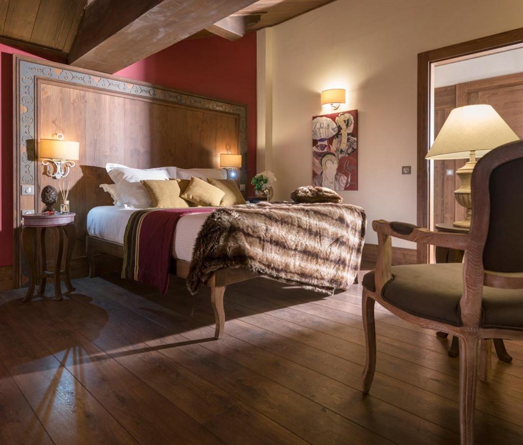 une chambre avec un grand lit et une chaise dans l'établissement Le Hameau du Kashmir, à Val Thorens