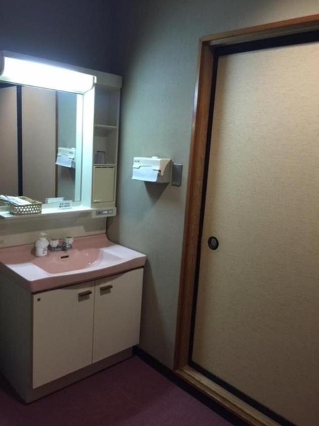 une salle de bain avec un lavabo rose et un miroir dans l'établissement Yuzawa Hotel, à Yuzawa