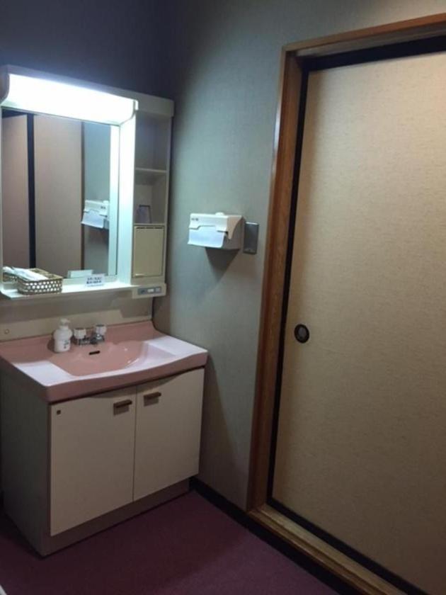 La salle de bains est pourvue d'un lavabo, d'un miroir et d'une porte. dans l'établissement Yuzawa Hotel, à Yuzawa