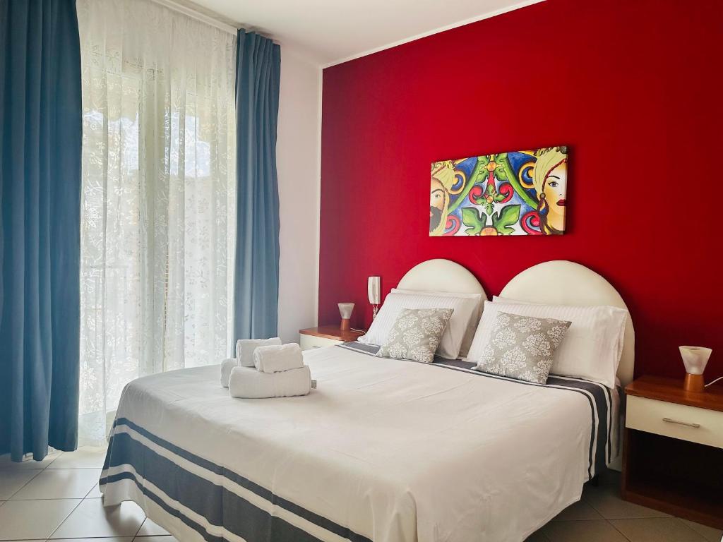- une chambre avec un mur rouge et un lit blanc dans l'établissement Riviera Ionica, à Santa Teresa di Riva