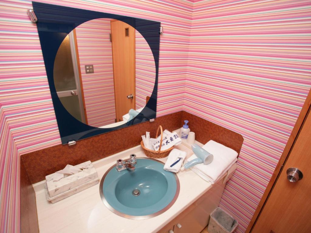 une salle de bain avec un lavabo et un miroir dans l'établissement Izuito Onsen Daitokan, à Itō
