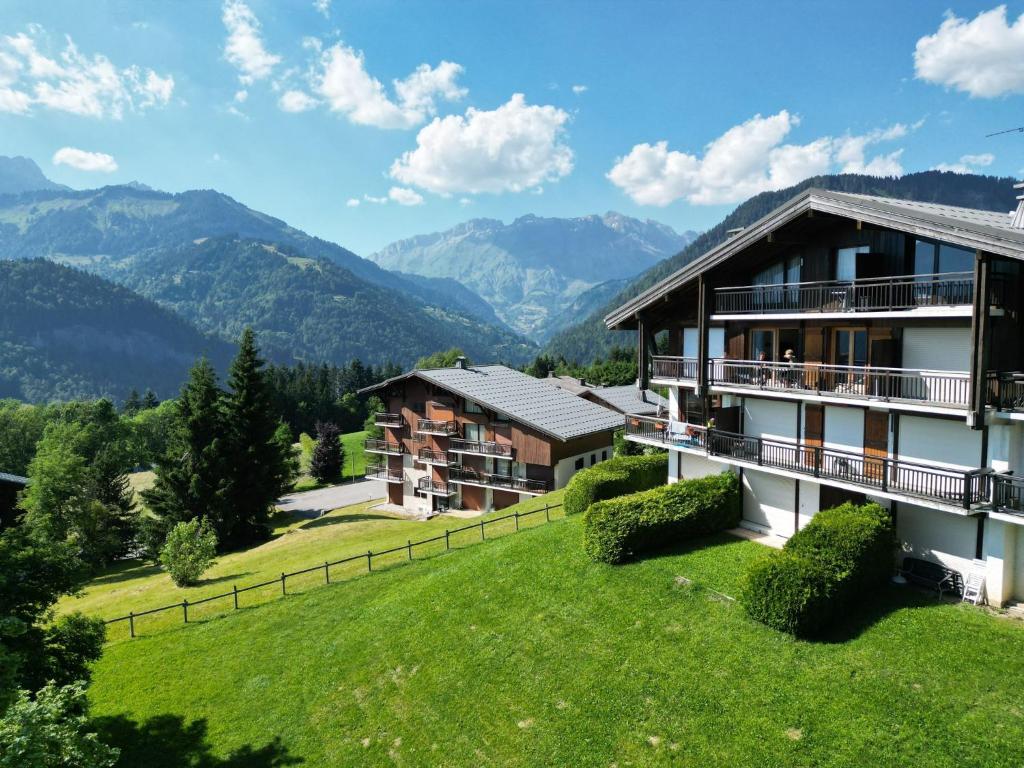 une maison sur une colline avec des montagnes en arrière-plan dans l'établissement Chalet Les Combes, à Notre-Dame-de-Bellecombe