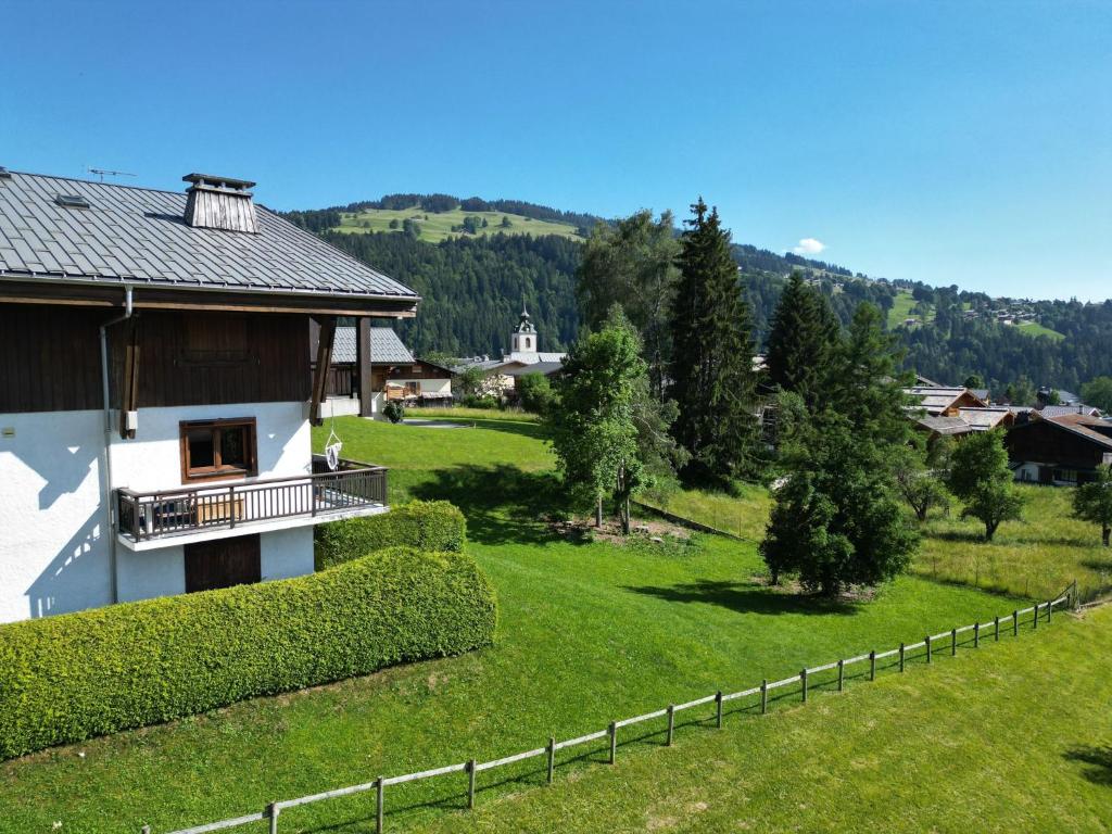 une maison dans un champ verdoyant avec une clôture dans l'établissement Chalet Les Combes, à Notre-Dame-de-Bellecombe