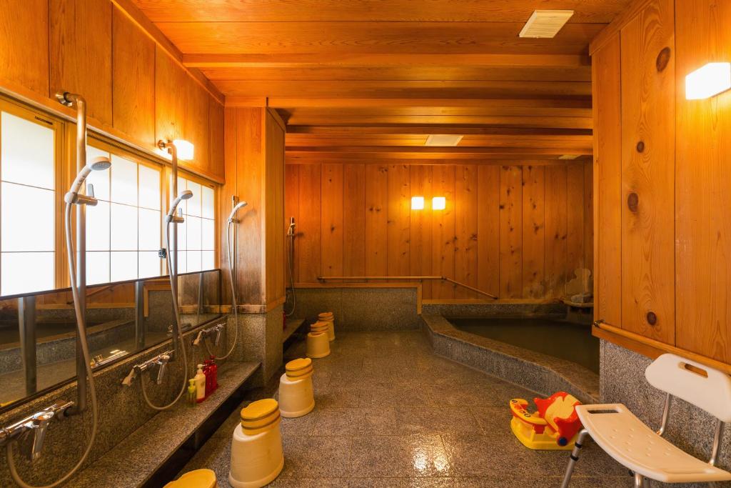 La salle de bains est pourvue de murs lambrissés et d'une baignoire. dans l'établissement Ryokan Asunaro, à Takayama