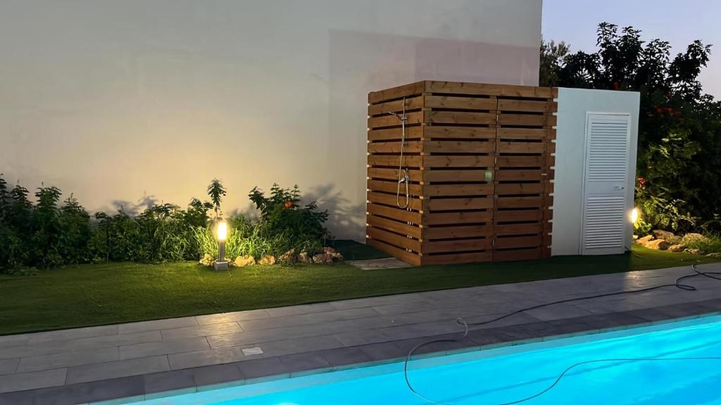 une cour arrière avec une piscine et un grand coffre en bois à côté d'un jardin dans l'établissement Villa Calimma, à Pachino