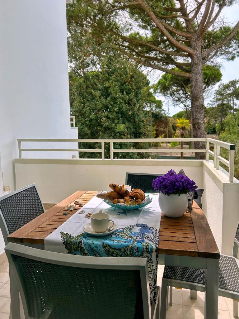 une table en bois avec un bol de nourriture sur un balcon dans l'établissement Dune Dependance, à Bibione