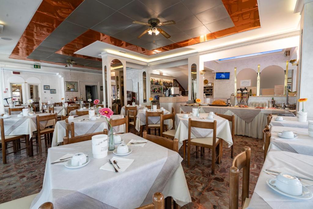 une salle à manger avec des tables et des chaises blanches dans l'établissement Hotel Britannia Rimini Marina centro, à Rimini