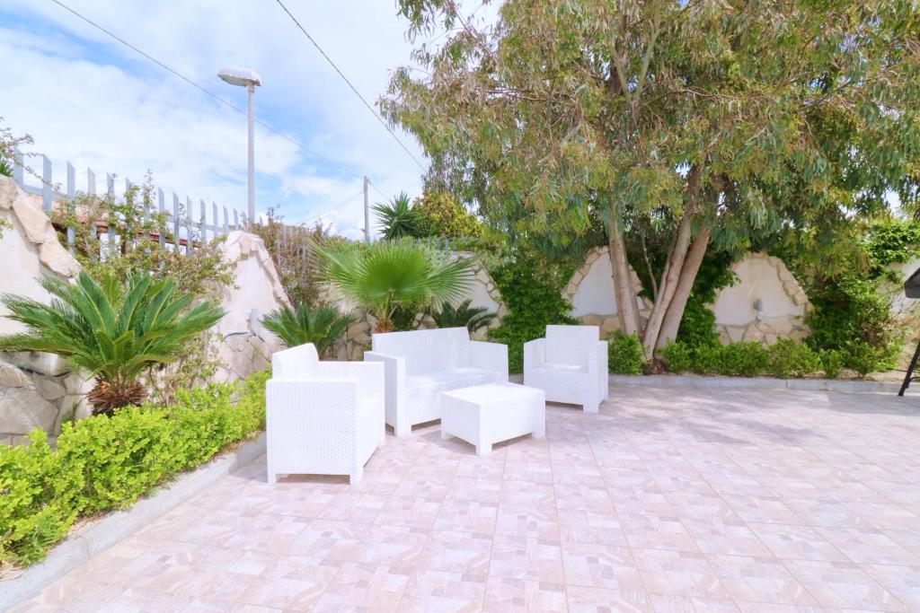 - un ensemble de chaises blanches assises sur une terrasse dans l'établissement Villa Primavera, à Castel Volturno