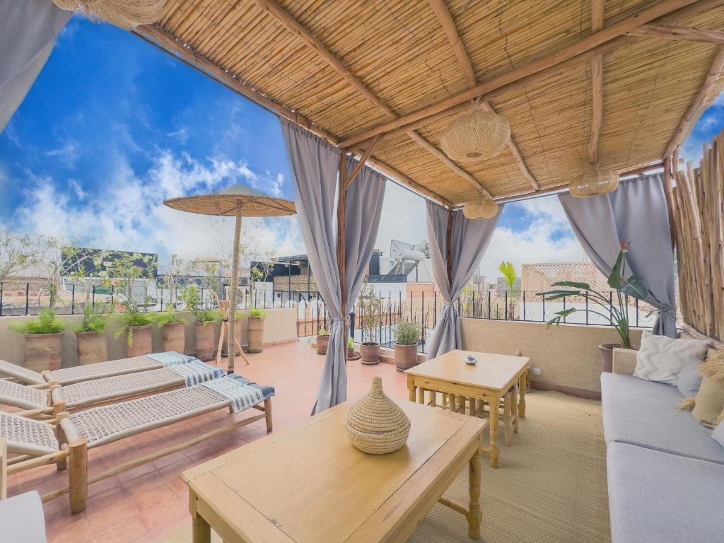 une terrasse avec des canapés, des tables et des parasols dans l'établissement Riad & SPA Privé - La Perle d'Orane - Marrakech, à Marrakech