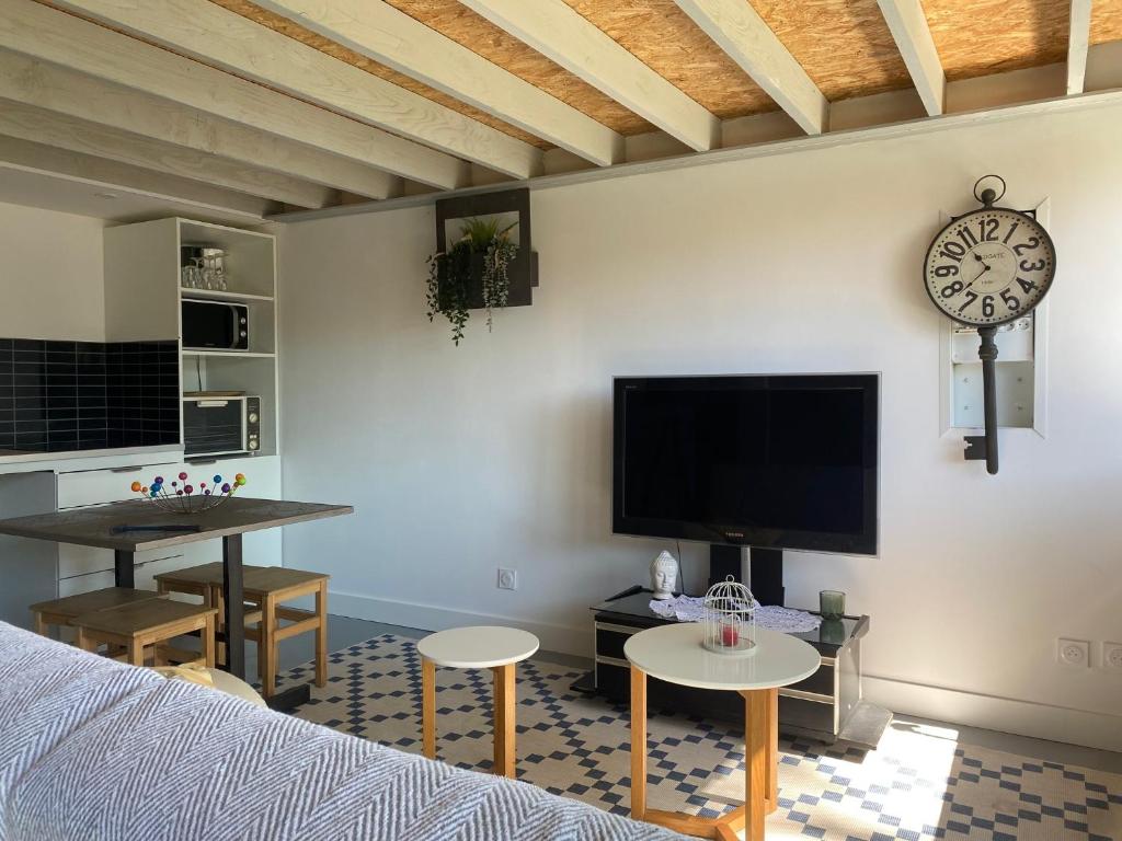 un salon avec un canapé et une horloge au mur dans l'établissement Gite d'ici et d'ailleurs 2 Maison proche Bordeaux et Bassin d Arcachon, à Saint-Morillon