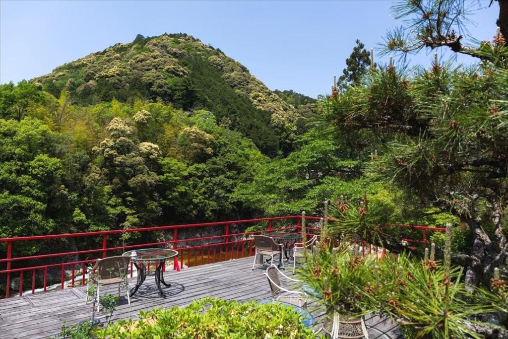 une table et des chaises sur une terrasse avec une montagne dans l'établissement Yunokaze HAZU, à Shinshiro