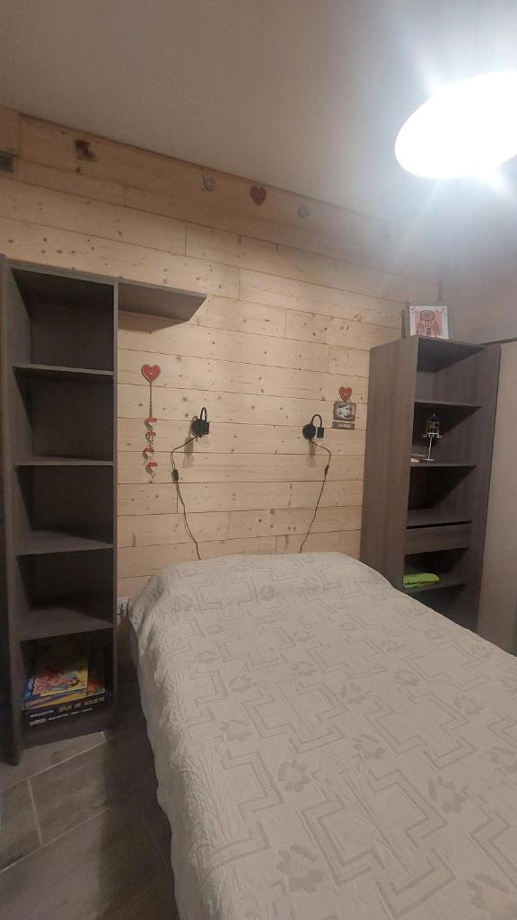 une chambre avec un lit et un mur en bois dans l'établissement Villa de la dore, à Le Mont-Dore