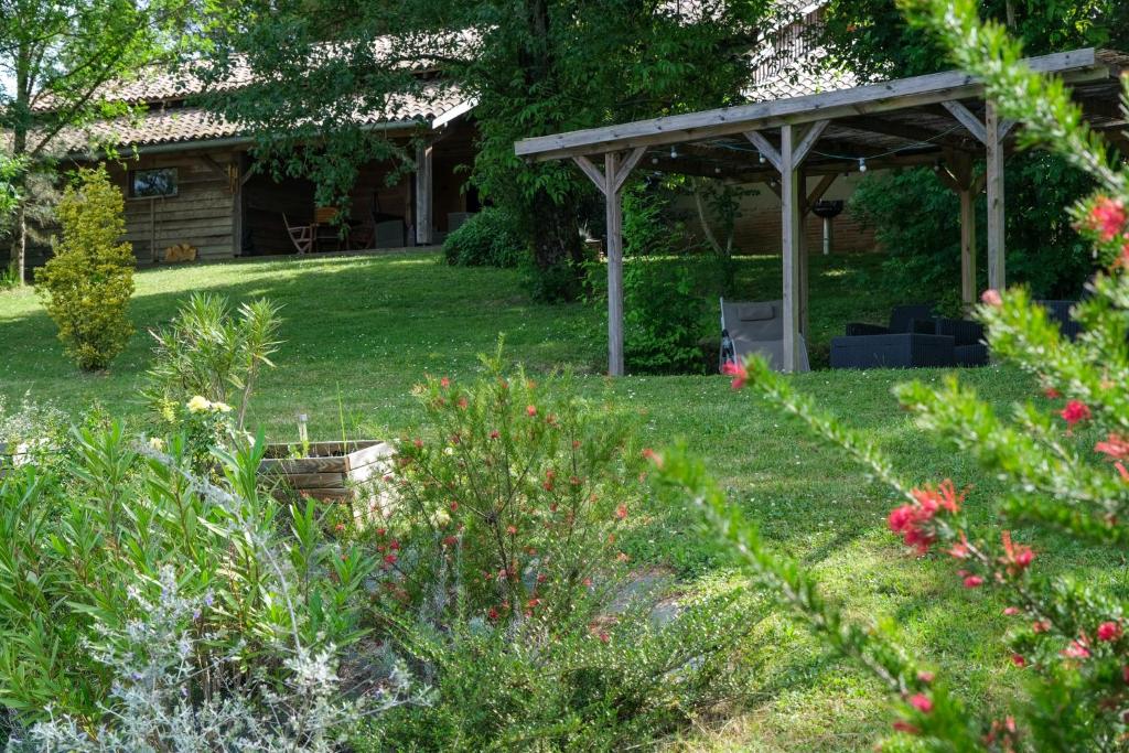 un jardin avec une pergola et quelques fleurs dans l'établissement Gîte Nat'ure, à Mirabel