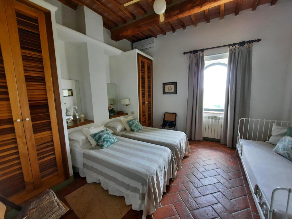 une chambre avec deux lits et une fenêtre dans l'établissement Pasqui Villas La Capanna accogliente casa in paese con vista piscina WiFi, à San Giovanni dʼAsso 29 autres photos