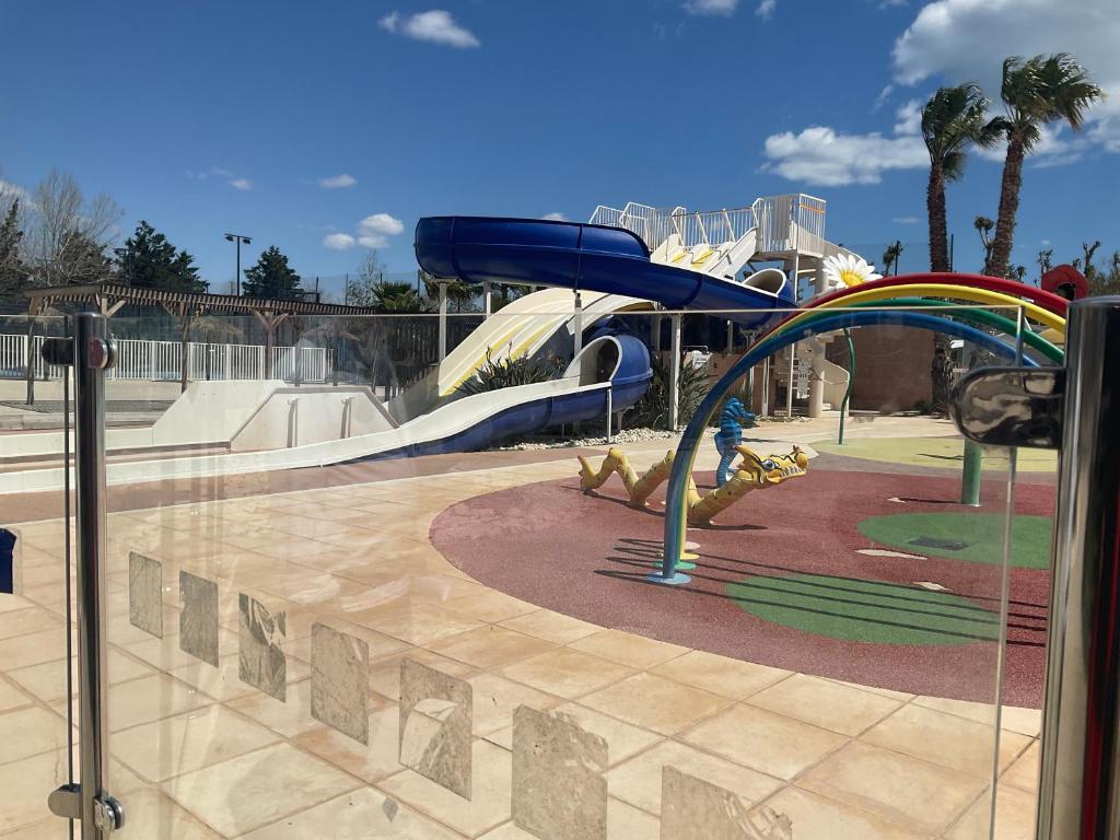 une aire de jeux avec un toboggan dans un parc dans l'établissement camping siblu sable du midi, à Sérignan