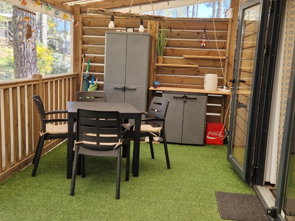 d'une terrasse avec une table, des chaises et un réfrigérateur. dans l'établissement Les Dunes de Contis, à Saint-Julien-en-Born
