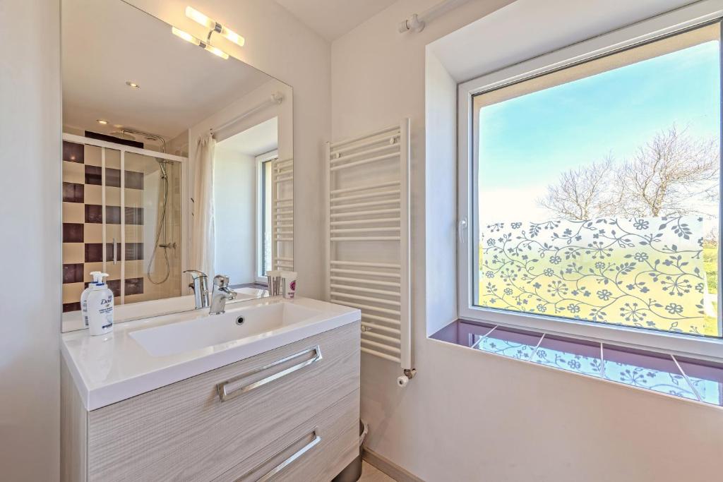 une salle de bain avec un lavabo et une grande fenêtre dans l'établissement Gîte avec piscine privée chauffée, à Plouguerneau