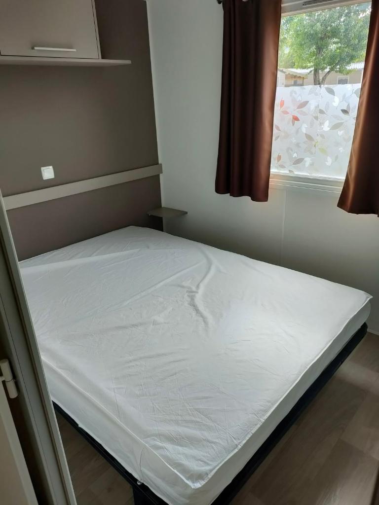 un lit dans une petite pièce avec une fenêtre dans l'établissement Mobil-home Siblu Les Rives de Condrieu, à Condrieu 11 autres photos