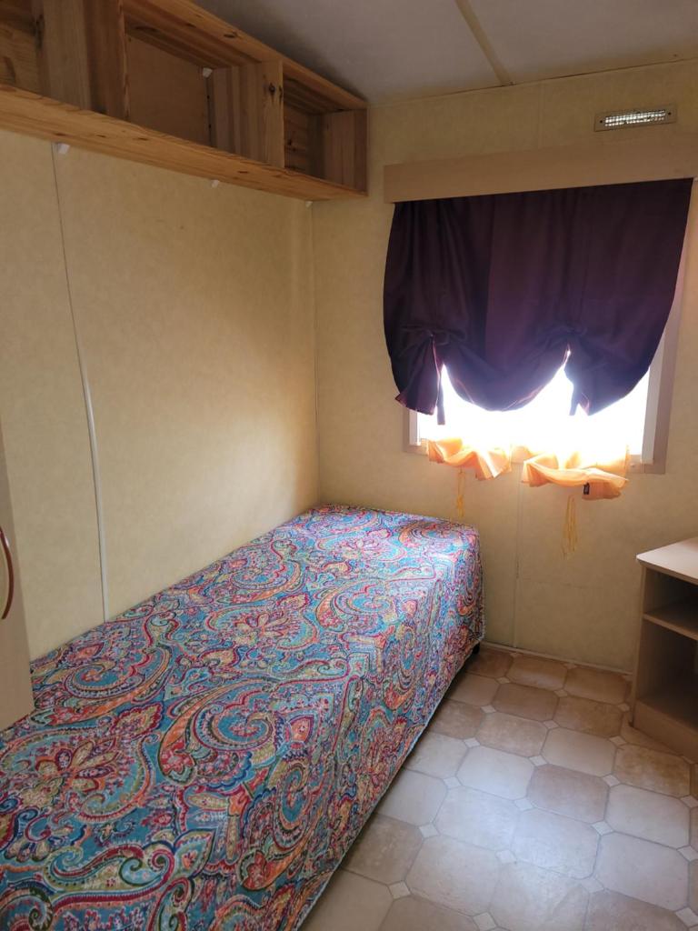 un lit dans une petite pièce avec une fenêtre dans l'établissement Mobil home Camping Bleu Marine, à Sérignan