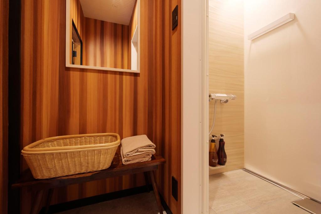 une salle de bain avec un panier en osier sur une étagère à côté d'une douche dans l'établissement Arifuku Onsen Yoshidaya, à Gotsu